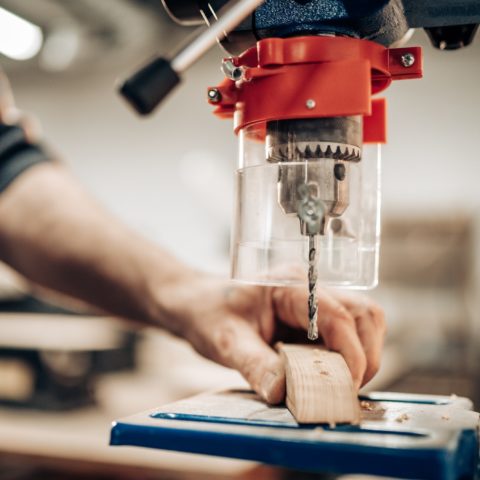 Carpenter makes hole in wooden part with drill press